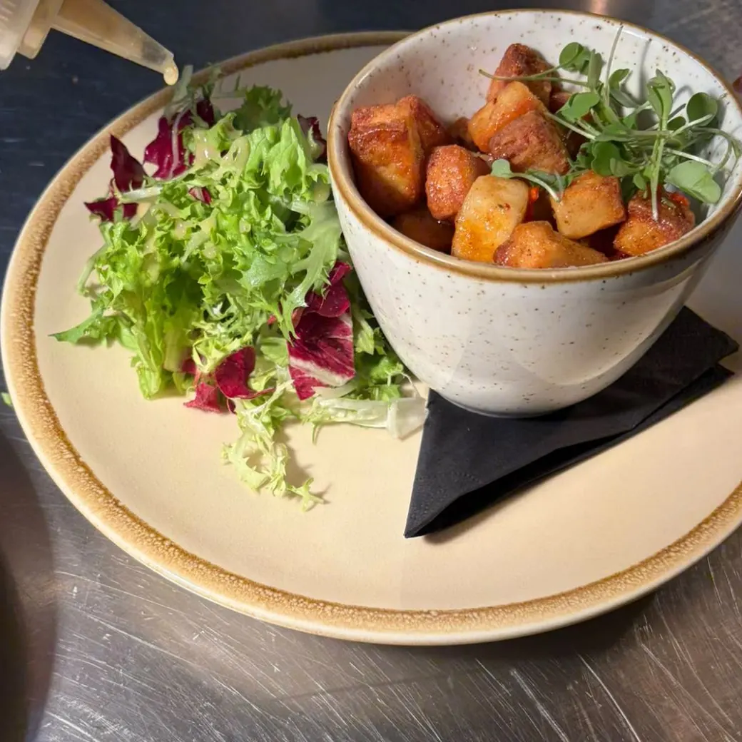 Crispy halloumi in a speckled bowl with micro herbs, beside dressed frisée and radicchio