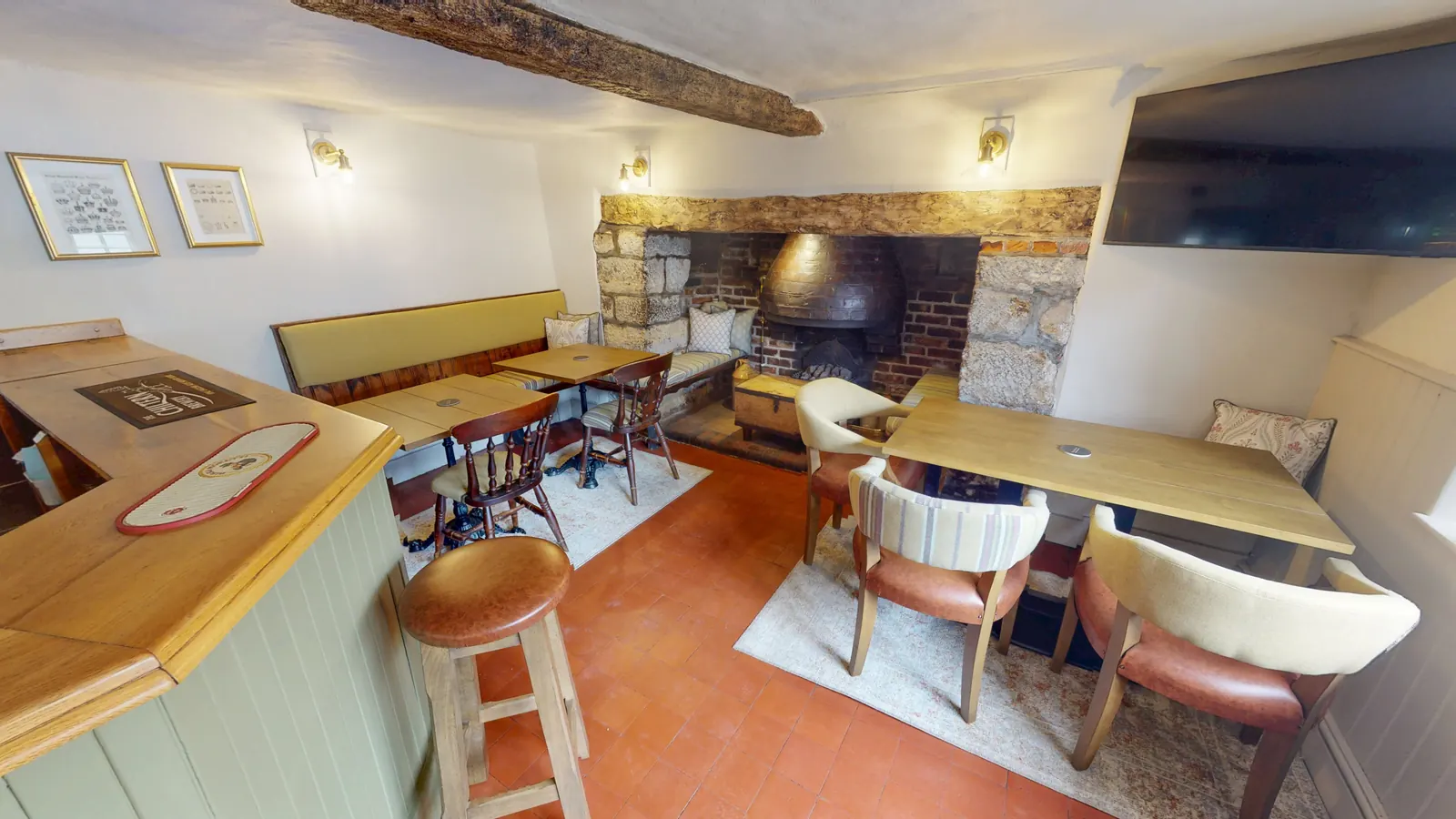 Tables and armchairs beside the inglenook fireplace in the bar