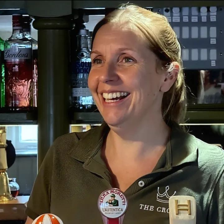 Abi, manager of The Crown, behind the bar in a Crown polo shirt